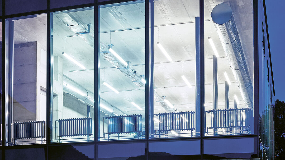 Bei Nacht wird ein ungehinderter Einblick in das beleuchtete Gebäude gewährt. Die Technik im Gebäude wird sichtbar.