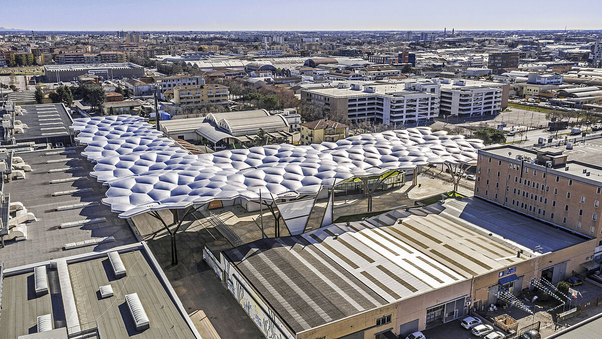 Tels des nuages, les modules disposés en L flottent au-dessus de l’entrée sud du parc des expositions de Vérone.