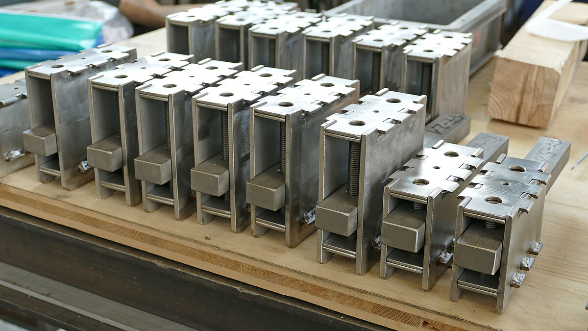 Die Justiermechanismen in der Werkstatt: Sie schaffen den Ausgleich zwischen dem gerundeten Pfosten-Riegel-Rahmen und dem an der Betondecke befestigten Halteprofil.