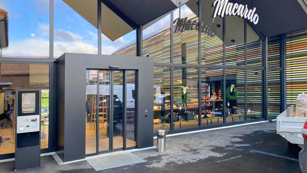 Façade d’entrée vers la boutique : construite dans le même style que la façade sud, la porte coulissante automatisée avec sas est accueillante et évite tout refroidissement non désiré de l’air ambiant.